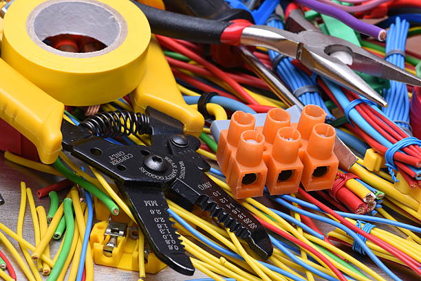 Electrical tools and cables used in electrical installations on grey metal background